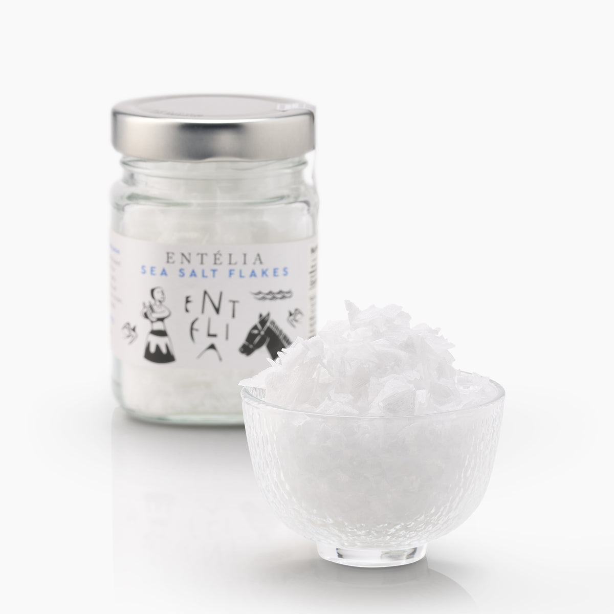 Entelia Pyramid Sea Salt Flakes 100g jar, and a glass bowl filled with its salt flakes.