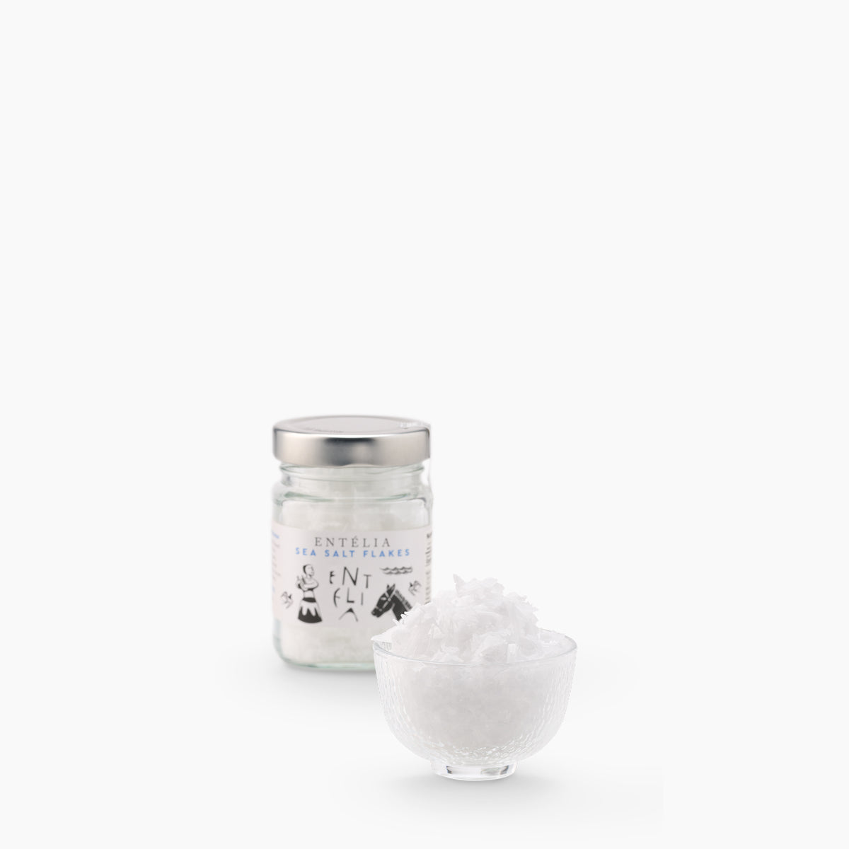 Entelia Pyramid Sea Salt Flakes 100g jar, and a glass bowl filled with its salt flakes.