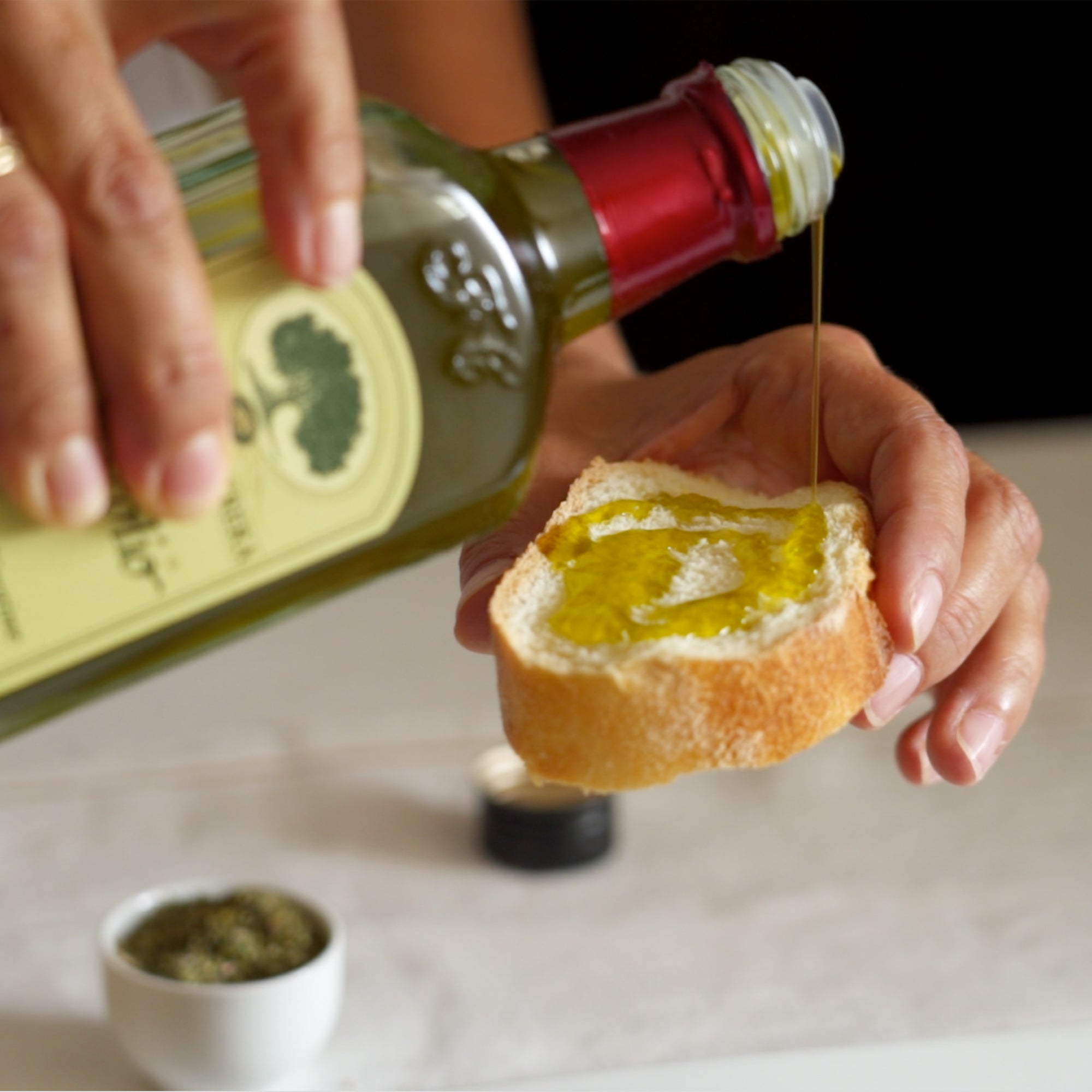 Frescolio Novello olive oil poured from a 500ml bottle onto bread.