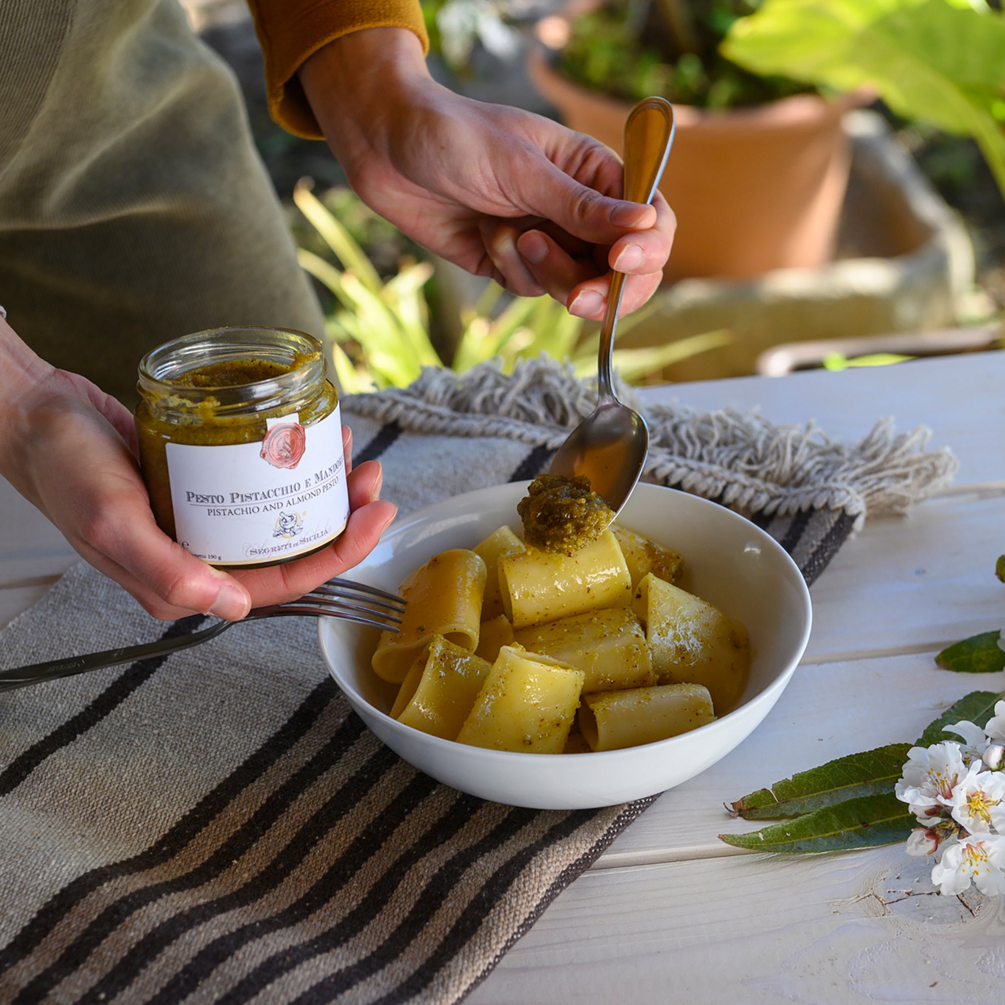 Spooning Frantoi Cutrera Pistachio and Almond Pesto from a 190g jar onto paccheri pasta.