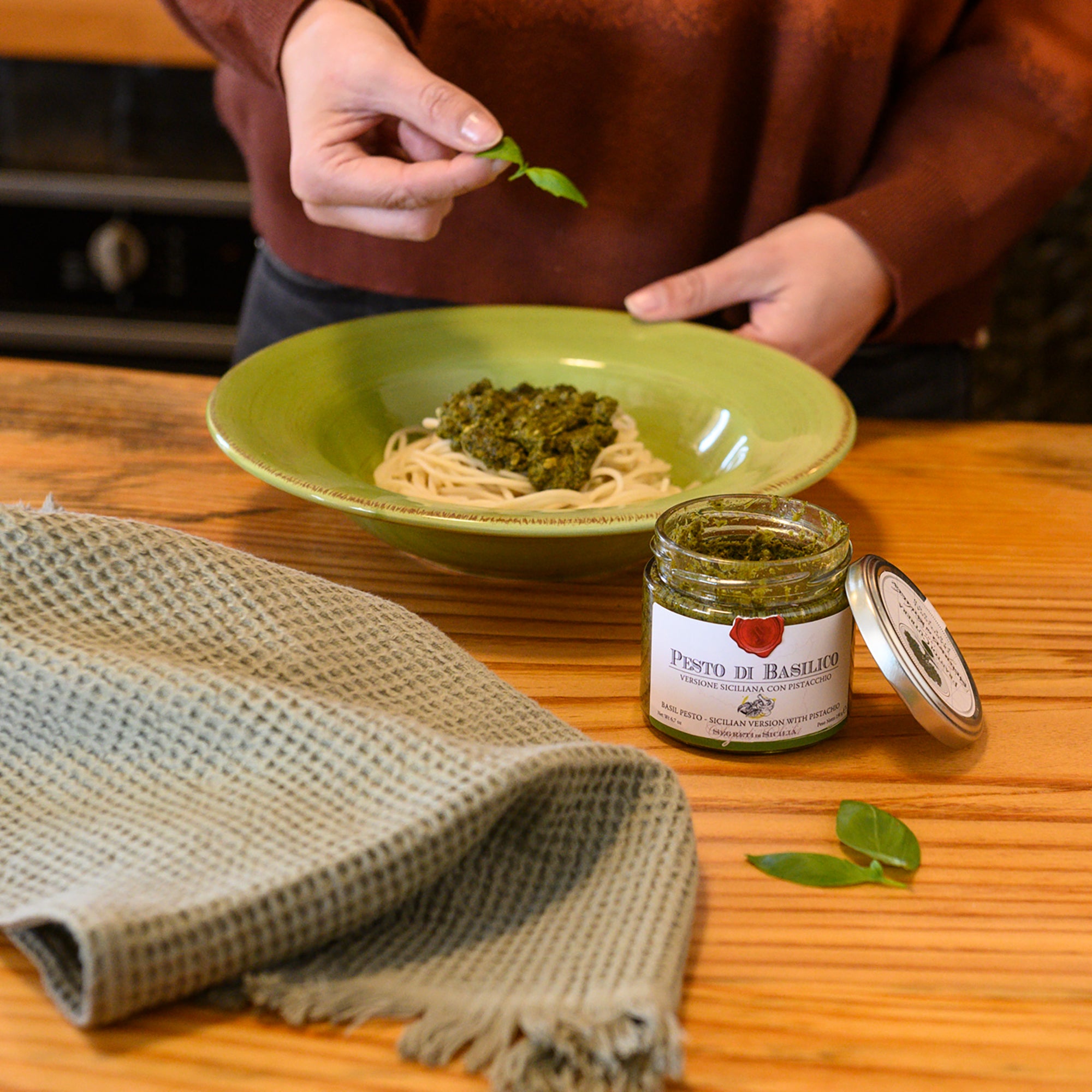 Garnishing pasta with Frantoi Cutrera Sicilian Basil Pesto.