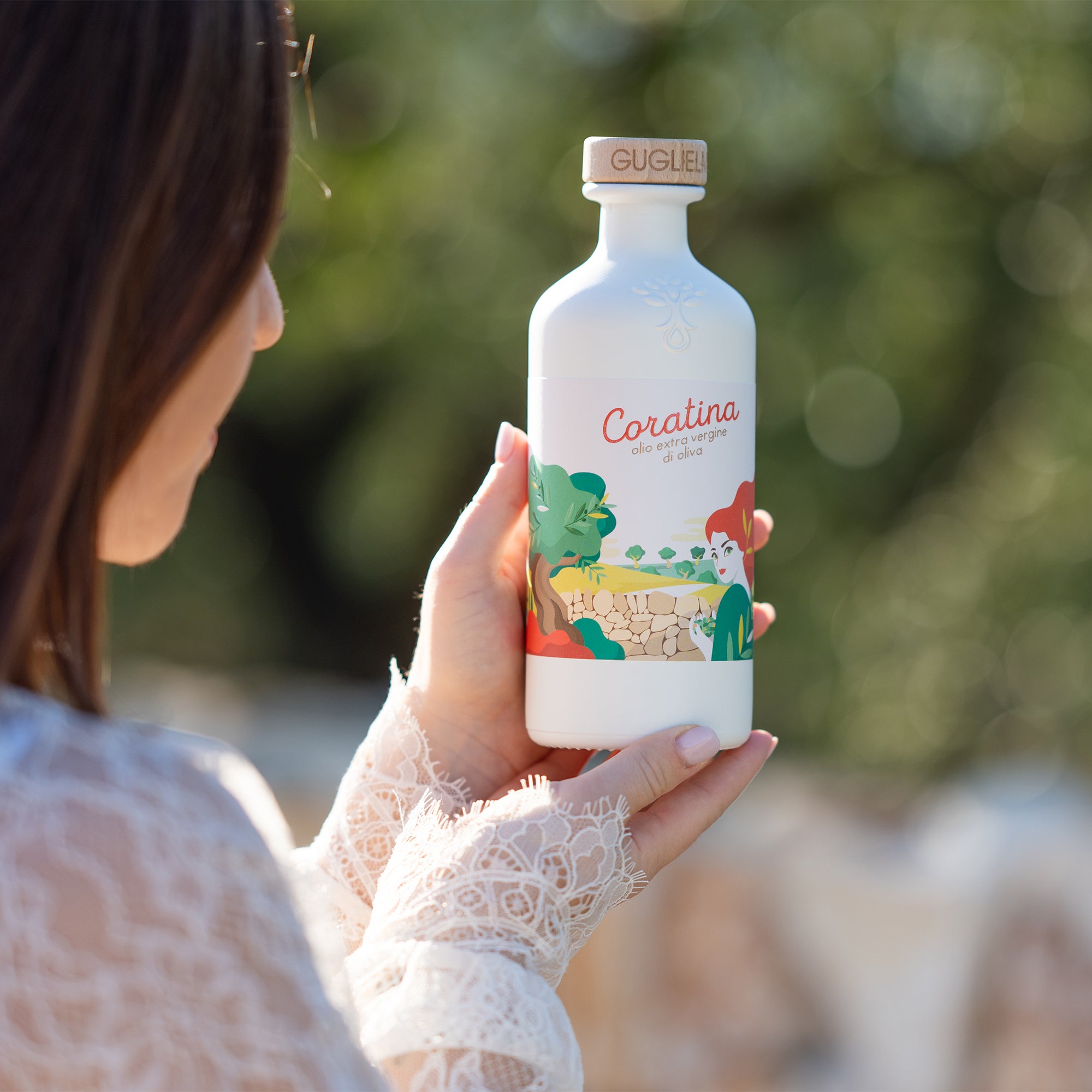 Woman holding a 500ml bottle of Guglielmi Le Monocultivar Coratina olive oil.