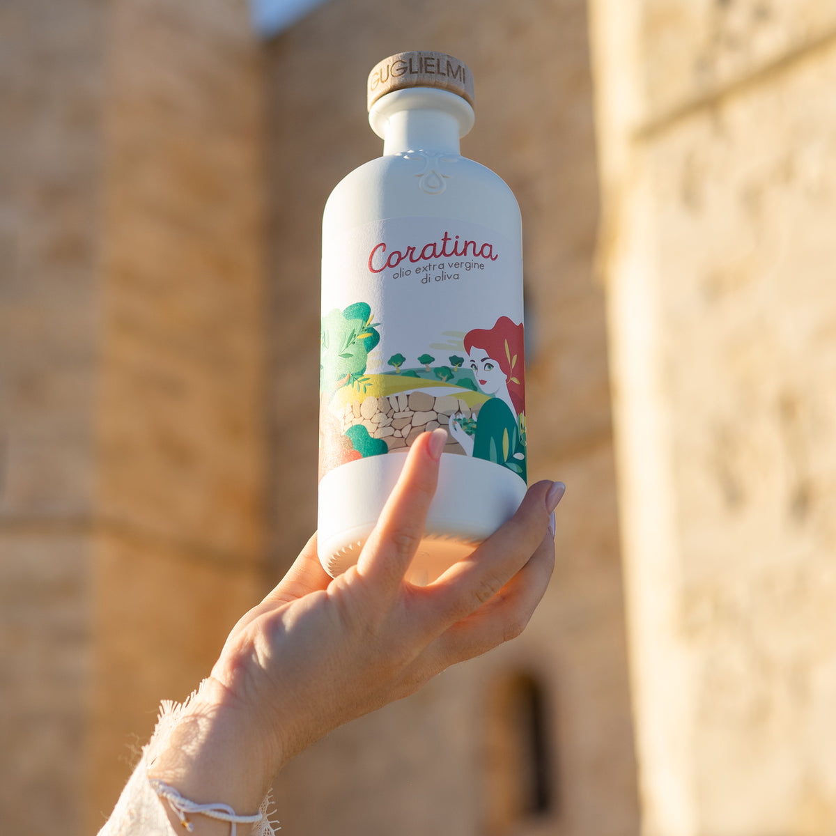 Holding a 500ml Guglielmi Le Monocultivar Coratina olive oil bottle.