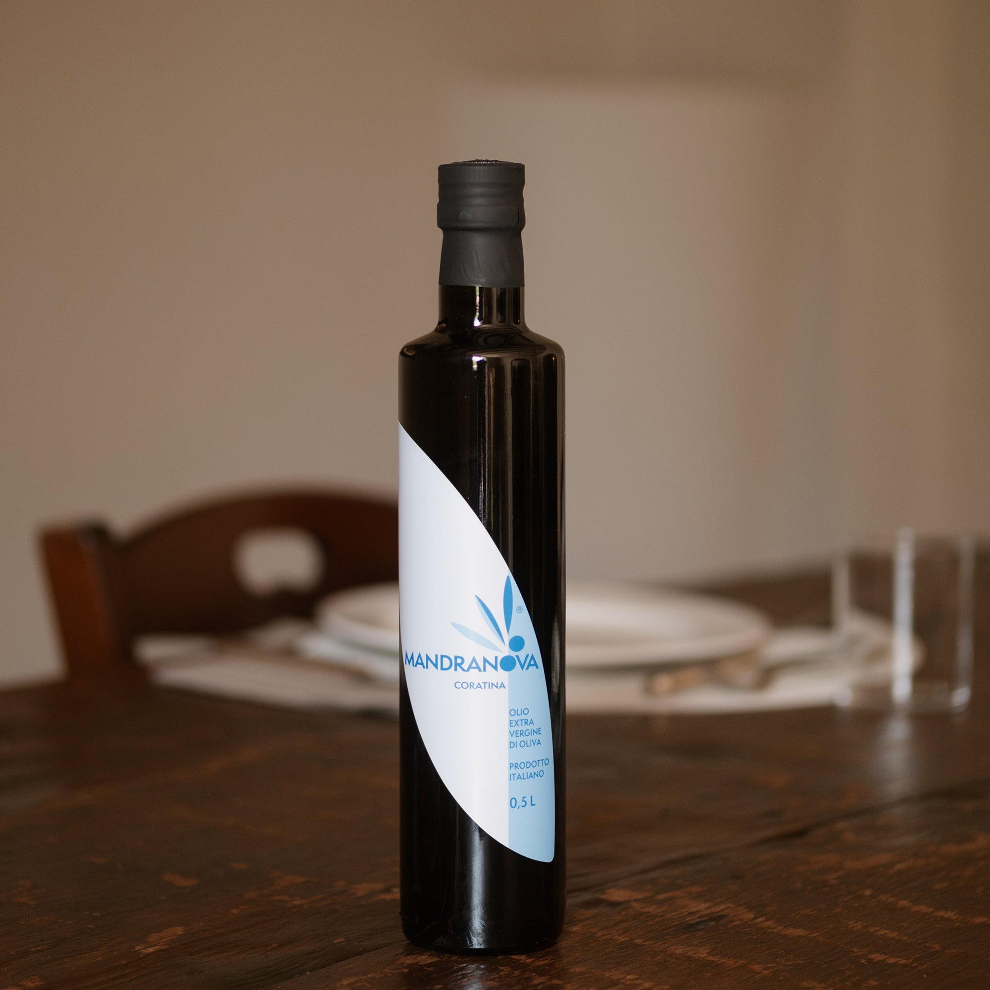 Mandranova Coratina 500 ml extra virgin olive oil bottle on a wooden dining table.