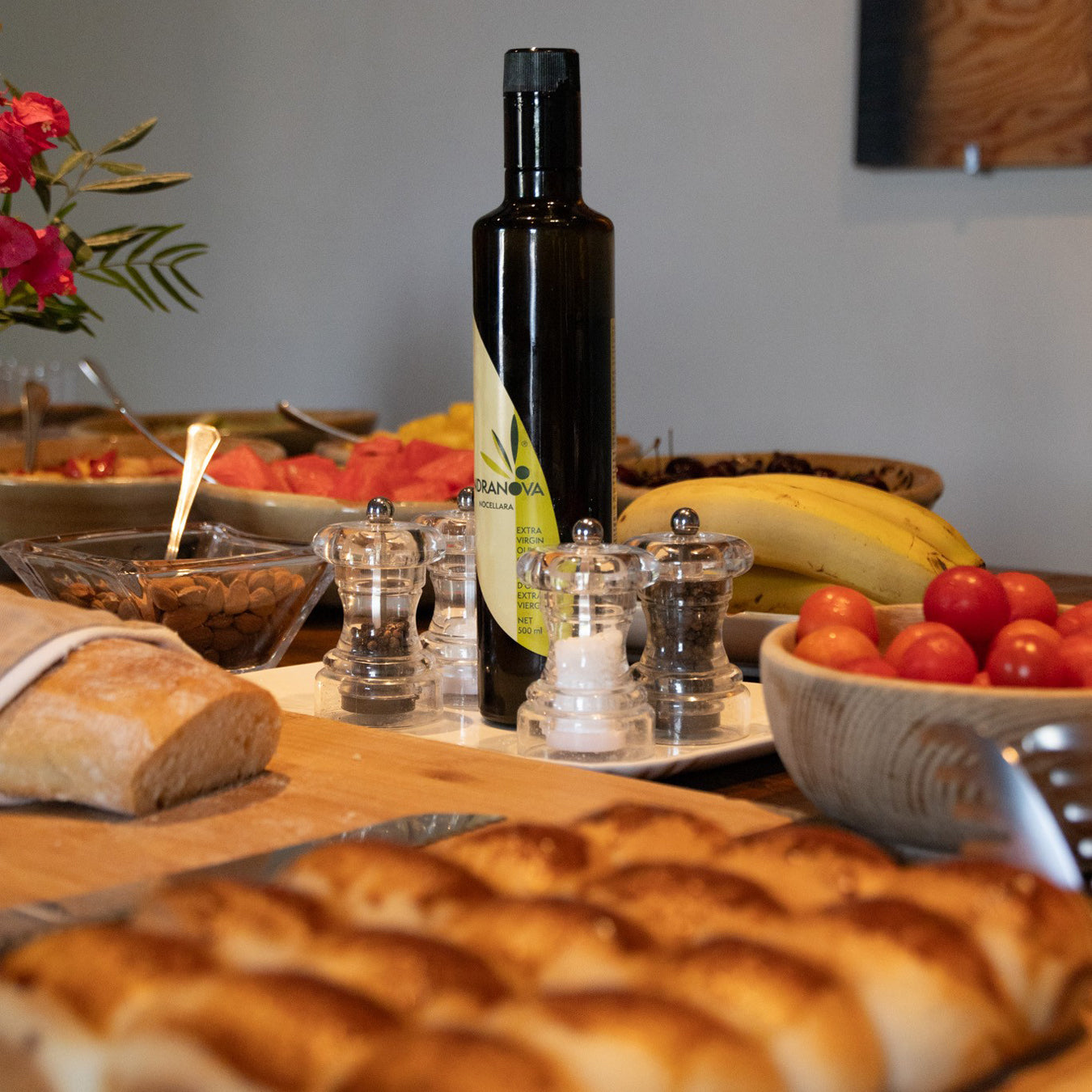 Mandranova Nocellara bottle among bread, tomatoes, bananas, nuts, and seasonings.