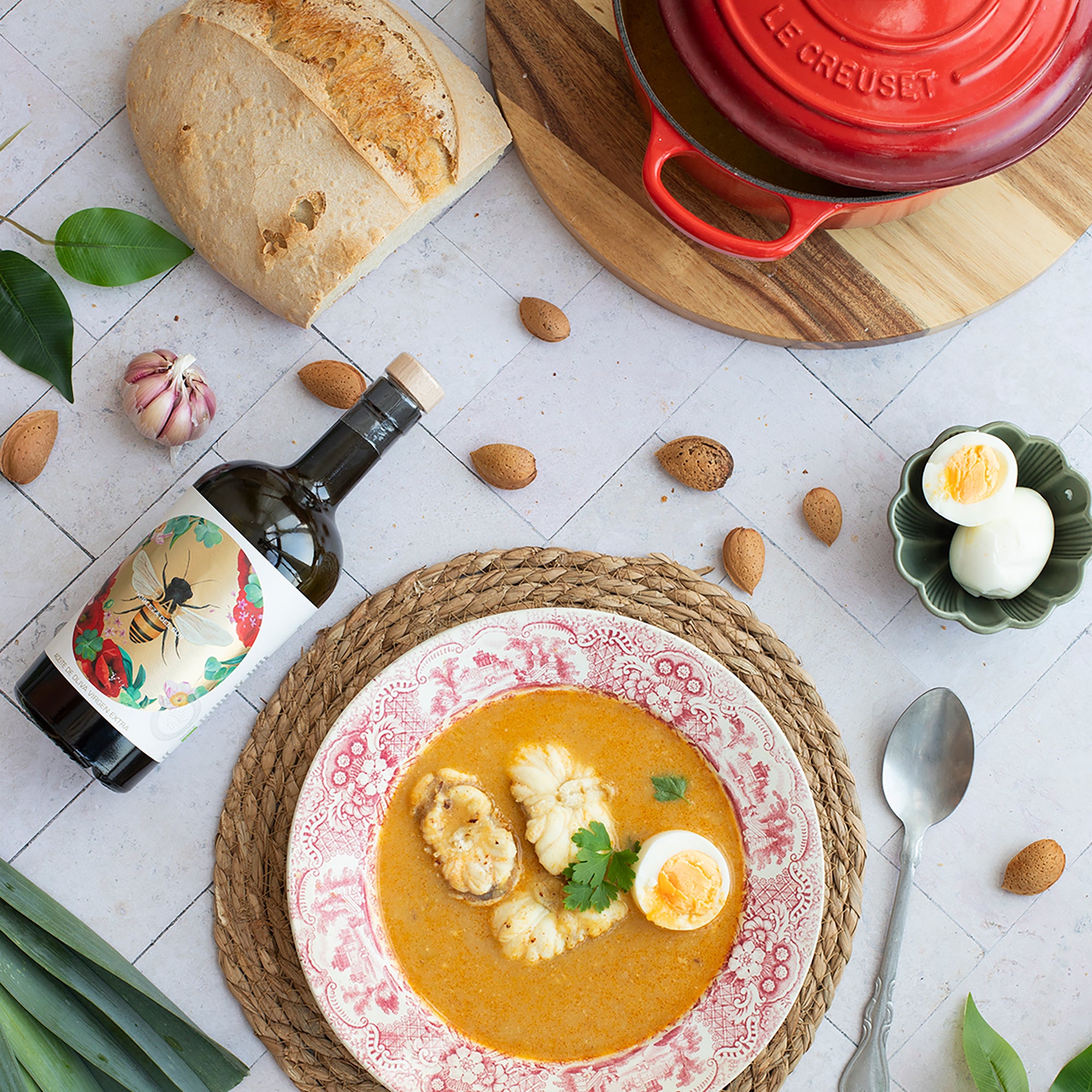 Nobleza del Sur Organic Day olive oil beside seafood soup, bread, eggs, and almonds.