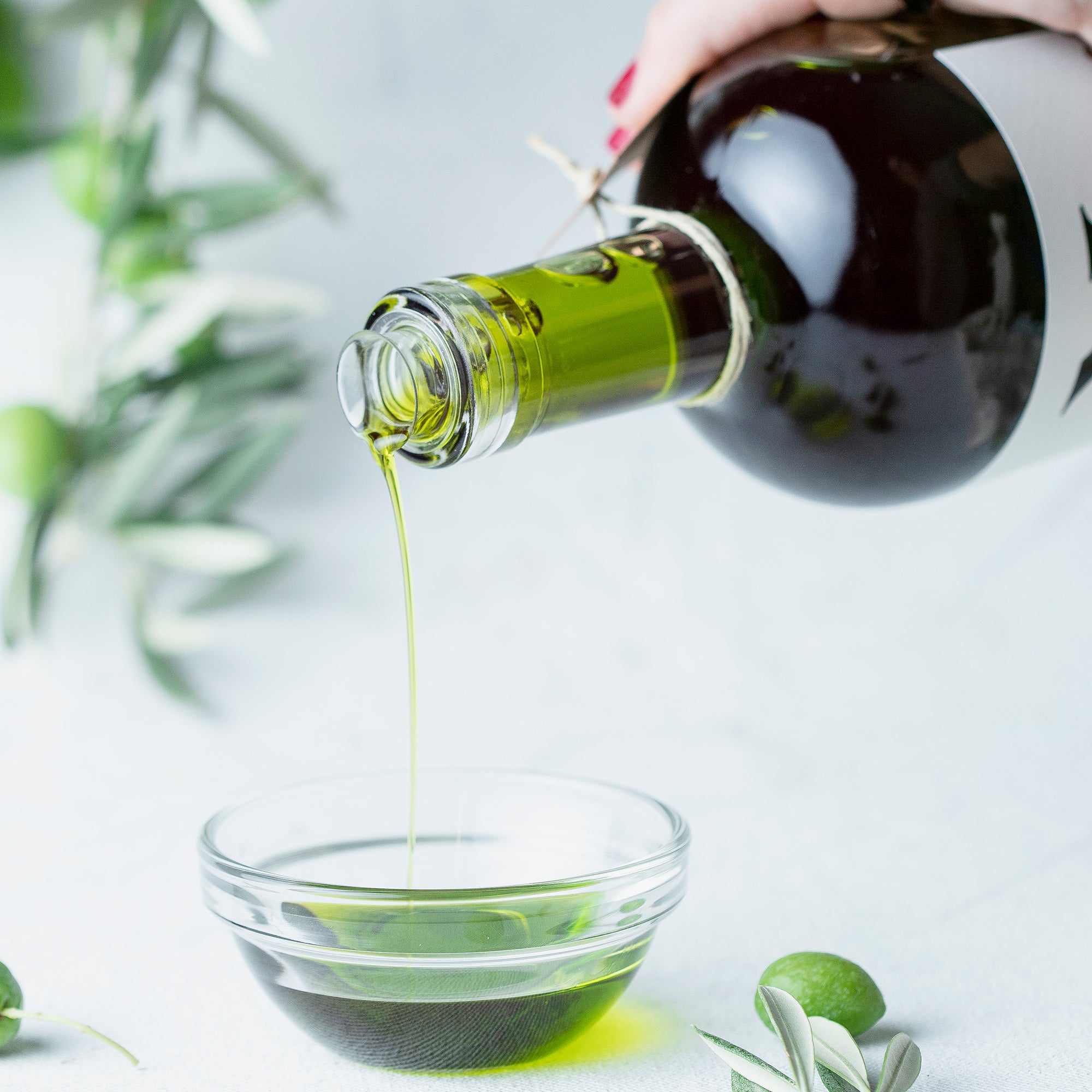 Pouring Nobleza del Sur Novo by Lola Sagra olive oil into a glass bowl.