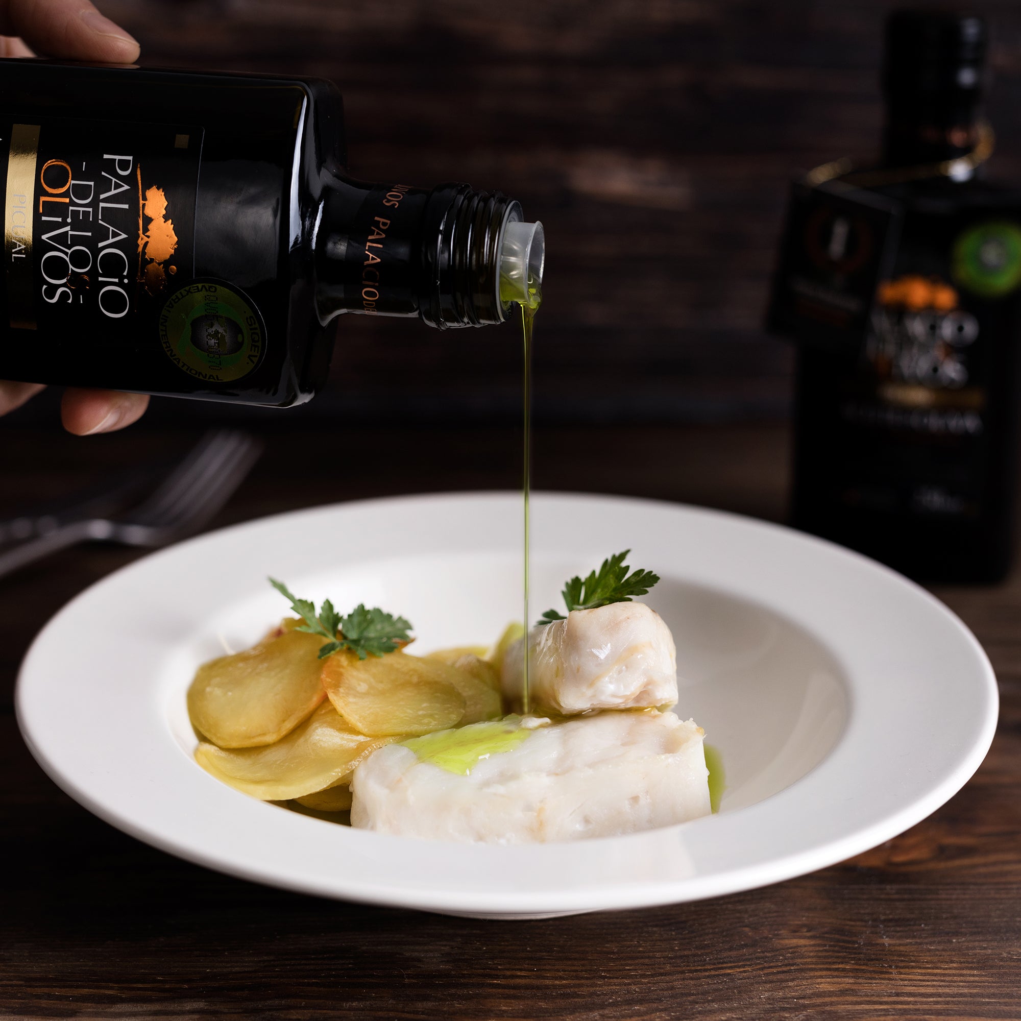 Palacio de los Olivos Picual olive oil poured over white fish, sliced potatoes, and parsley.