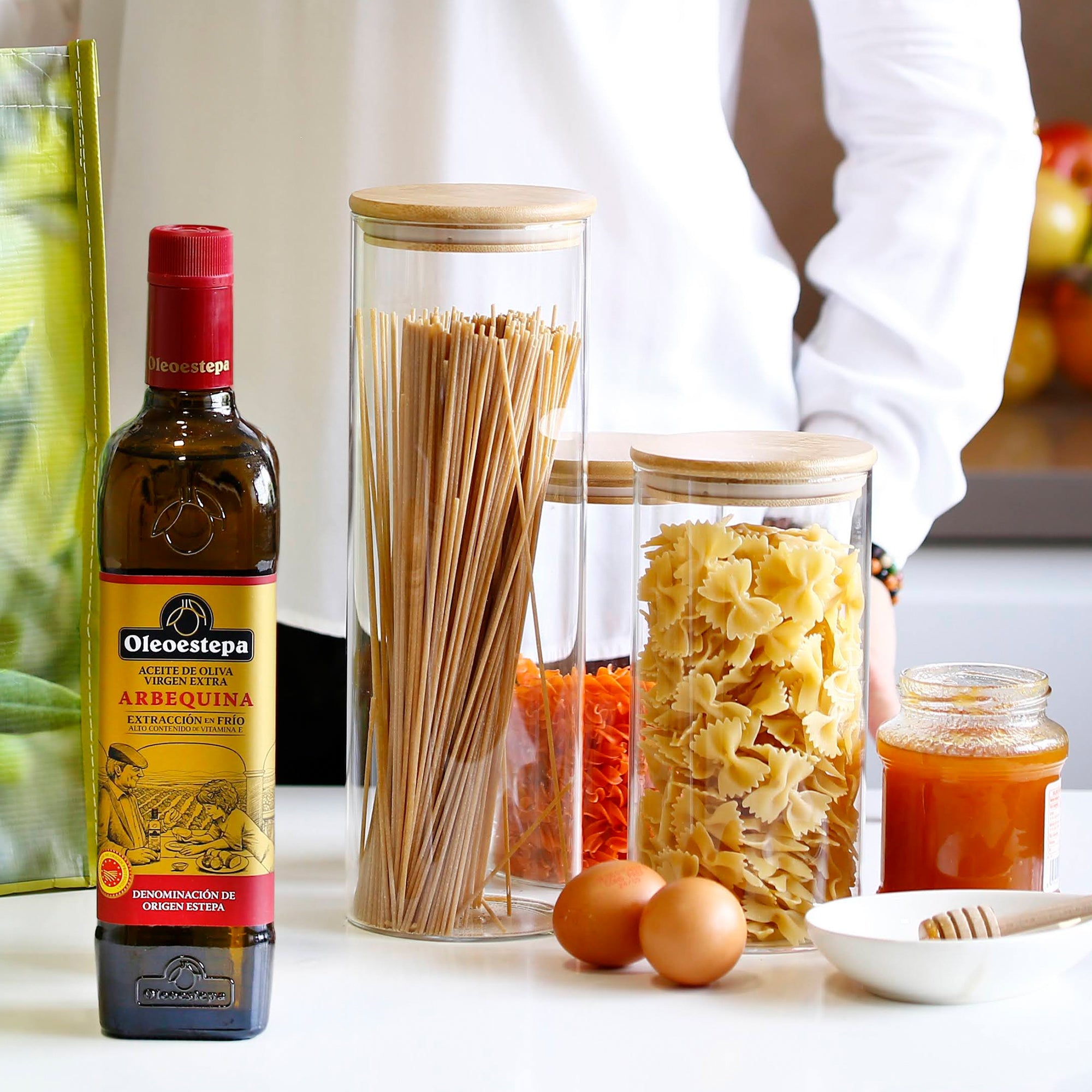 Oleoestepa Arbequina bottle beside pasta jars, eggs, and honey.