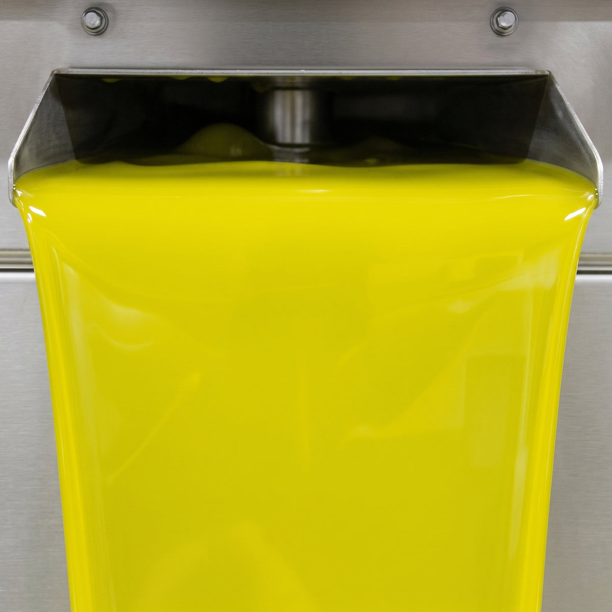 Bright green olive oil flowing from stainless-steel milling equipment at Oleoestepa.