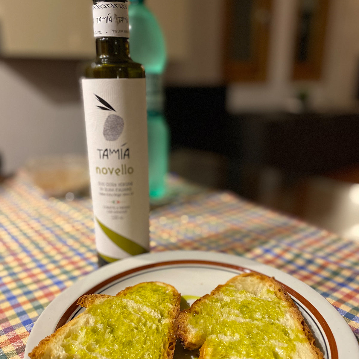 Slices of bread topped with green olive oil from a bottle of Tamia Organic Novello.