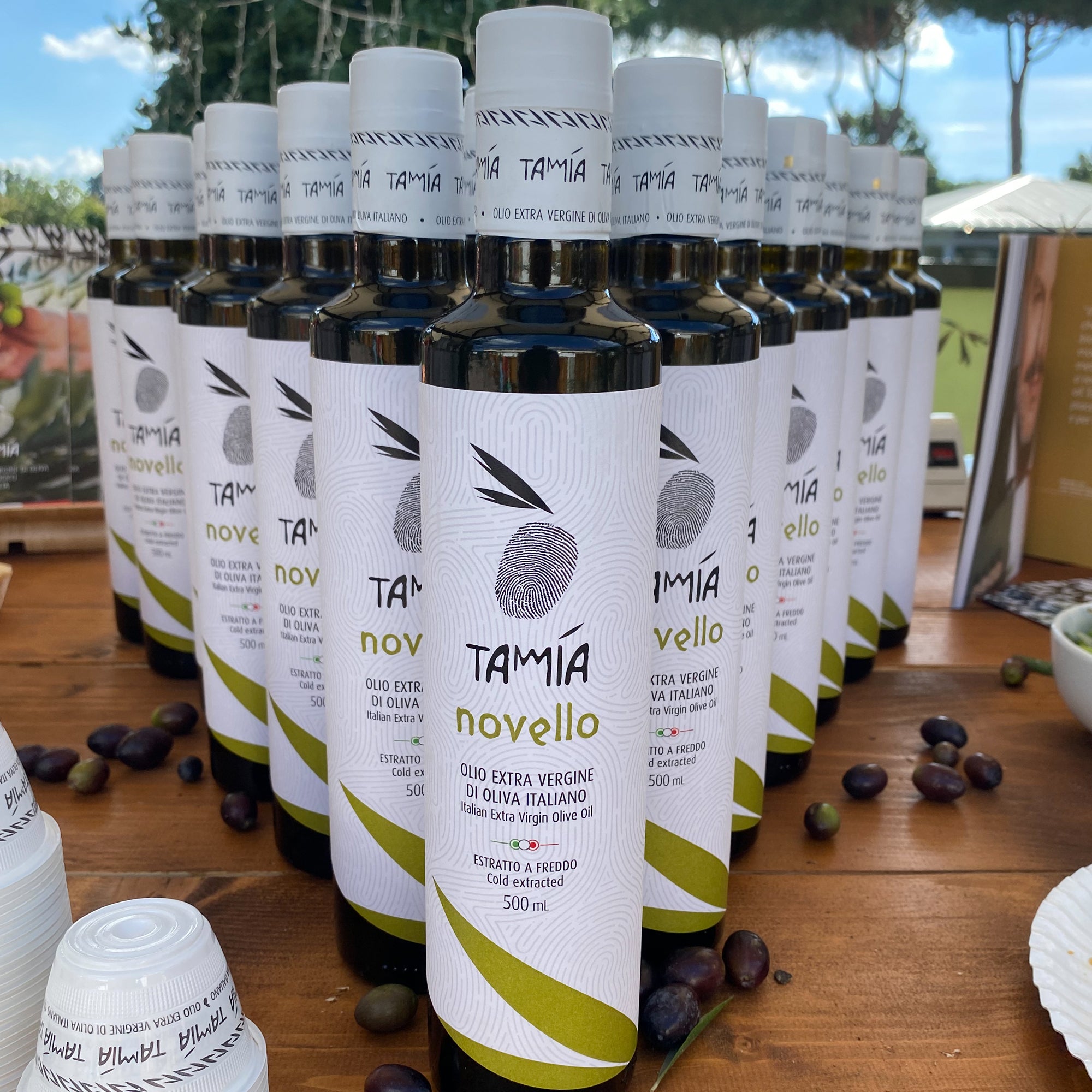 Rows of 500ml Tamia Organic Novello bottles, and scattered olives.