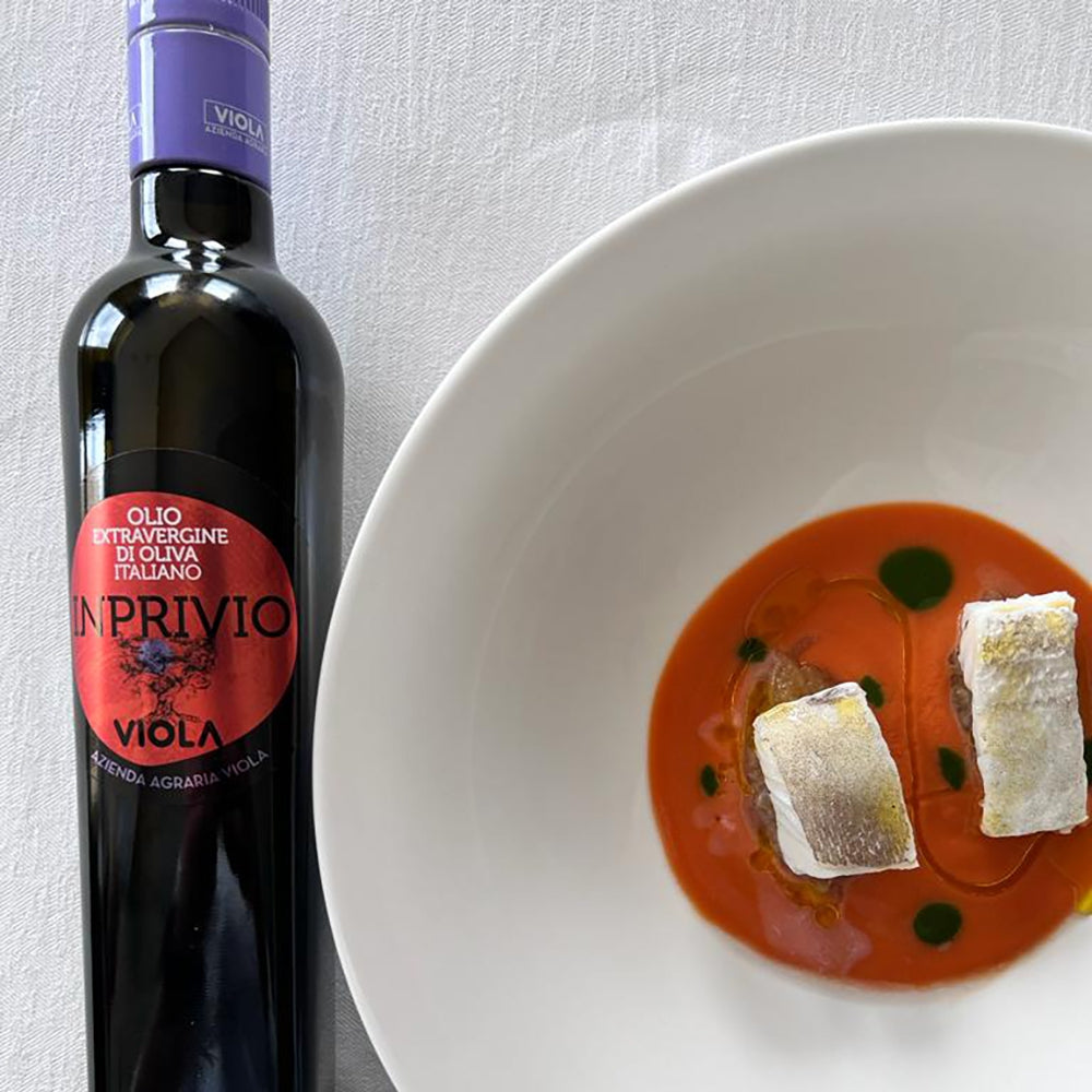 Viola Inprivio 500 ml bottle beside a plated fish dish with red sauce.