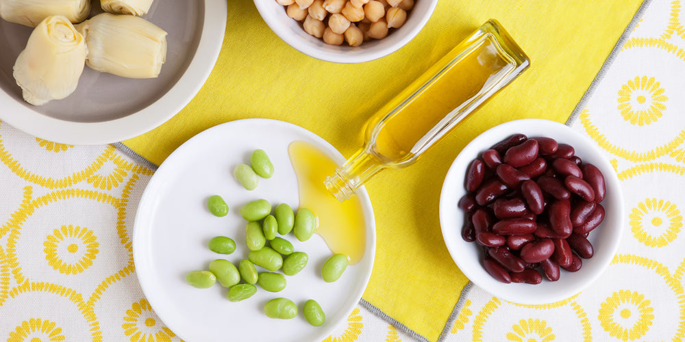 Olive oil bottle with green soybeans, red beans, chickpeas, and artichokes.