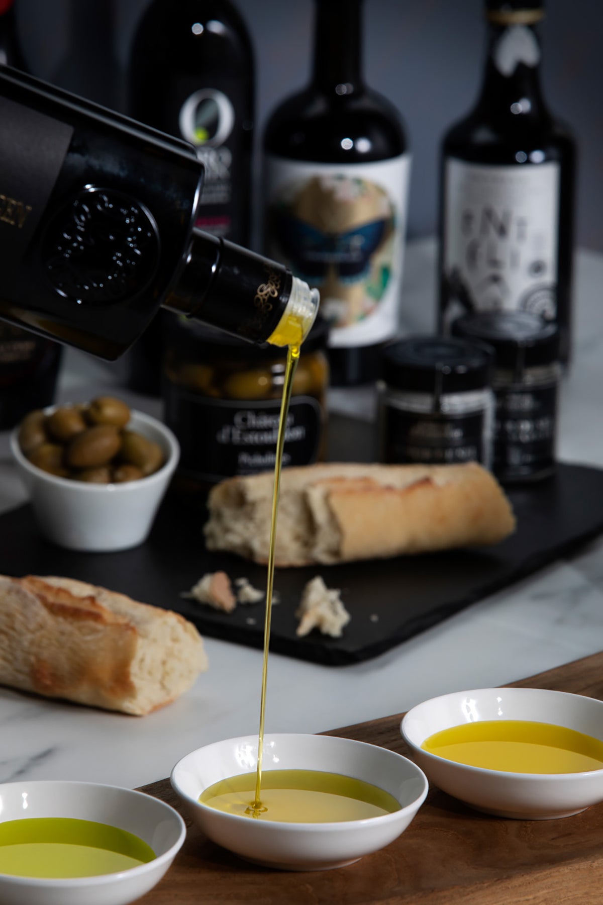 Olive oil being poured from an Oleoestepa Estepa Virgen bottle into small bowls.