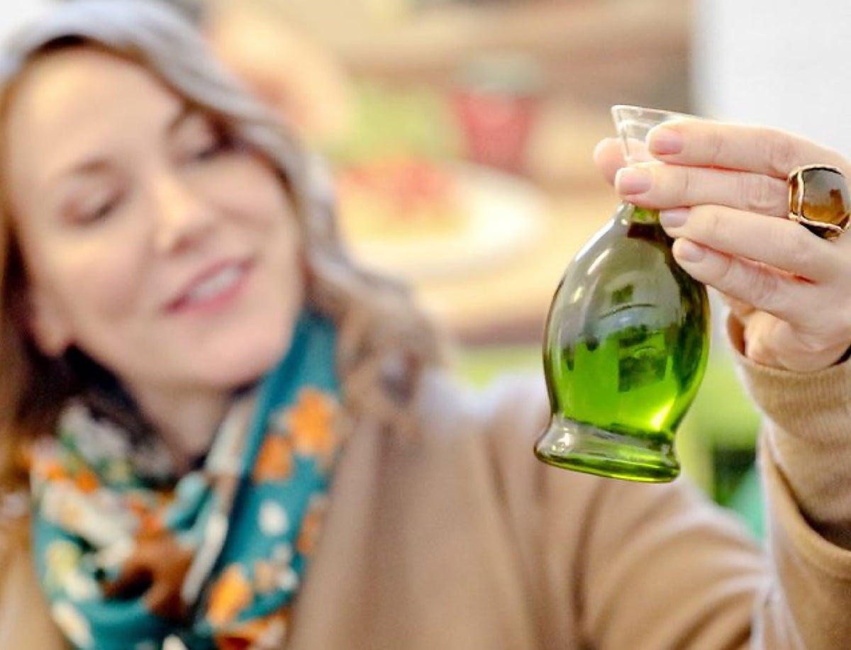 Joanne Lacina examining extra virgin olive oil in a small glass container.